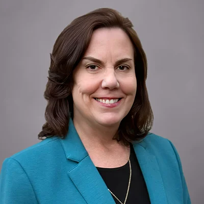 A headshot of Susan Barrick, a Director of First Impressions at SEIA, wearing a turquoise blazer, black shirt, and silver chain.